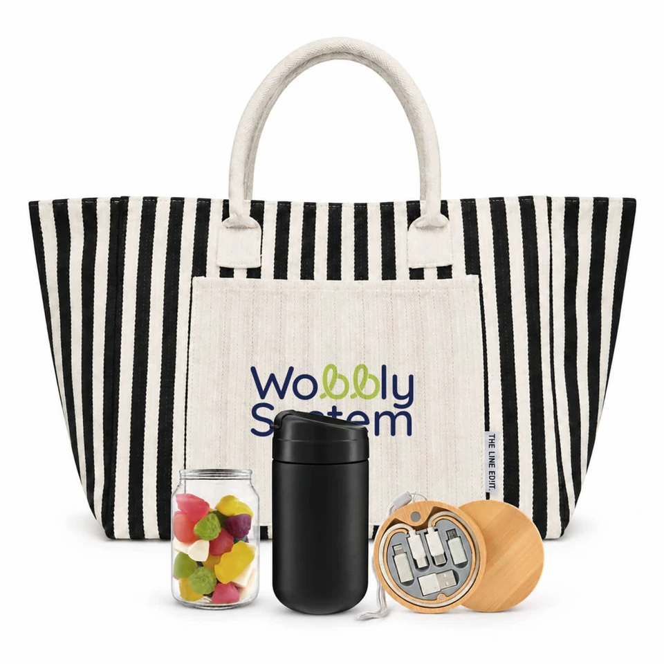 A striped tote bag in black and white with a cream pocket, a jar of colourful sweets, a black drink container, and a wooden item.