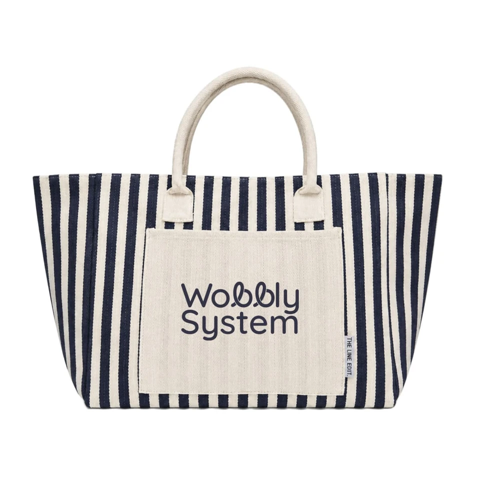 A large striped tote bag in navy and cream, featuring a front pocket with a logo.