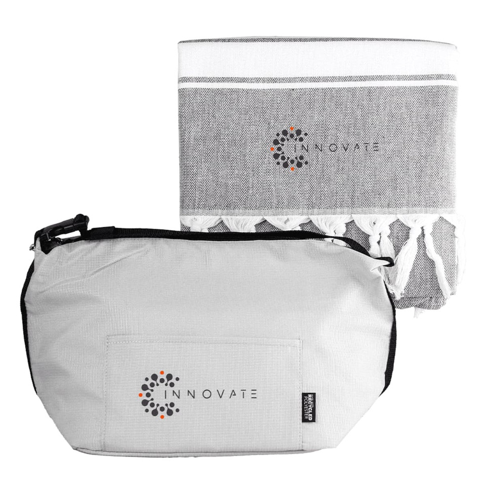 A grey cooler bag with a zipper and a matching grey towel featuring tassels. Both items have a logo.