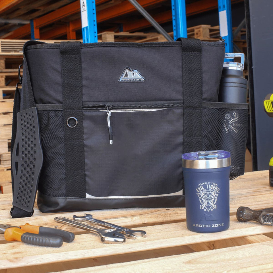 A black cooler bag with straps, featuring a front pocket and a branded drink bottle and cup beside it.
