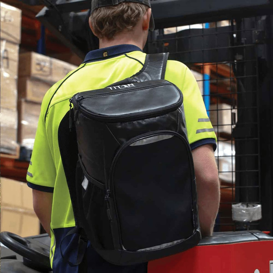 A black cooler backpack with a single shoulder strap, carried by a person wearing a bright yellow and navy uniform.