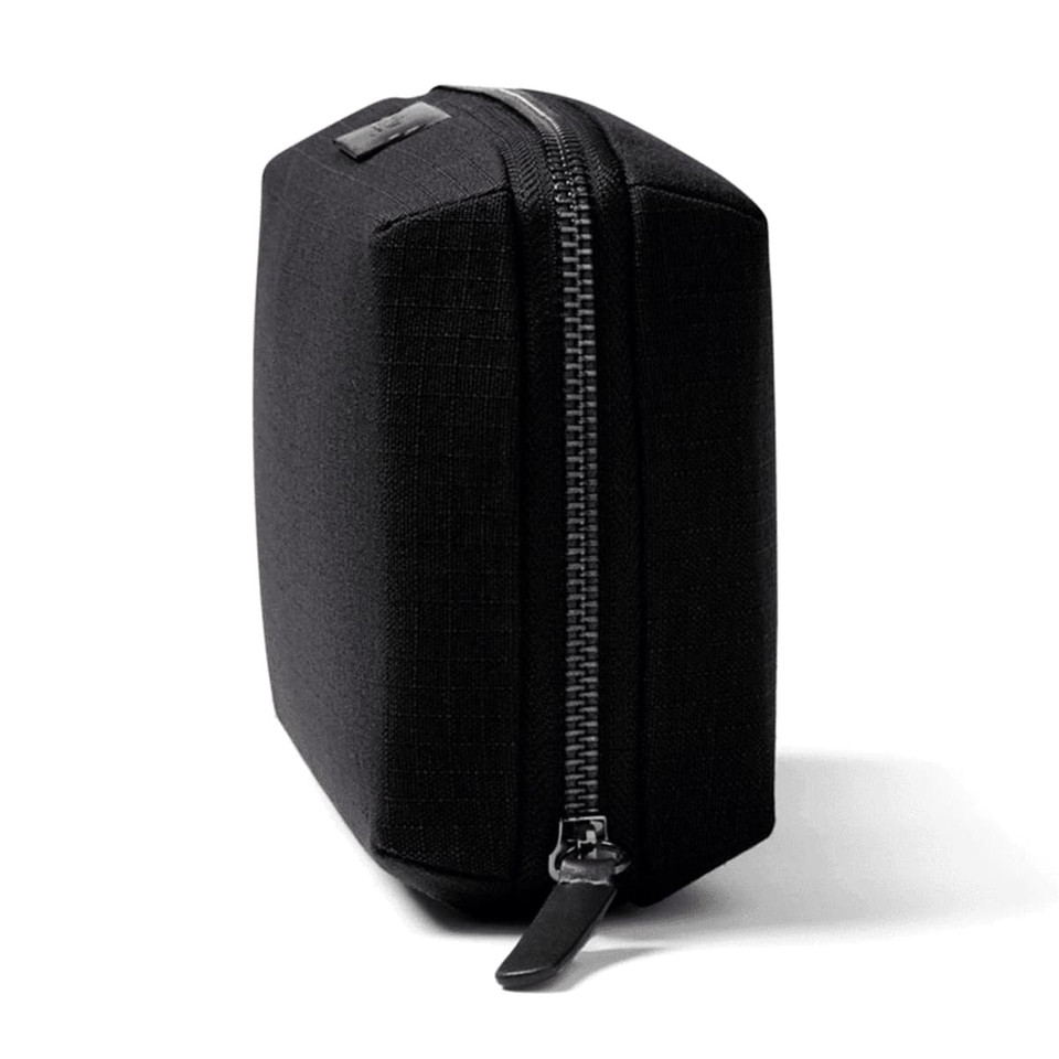 A black tech kit with a structured shape and a zipper closure, featuring one logo on the side.