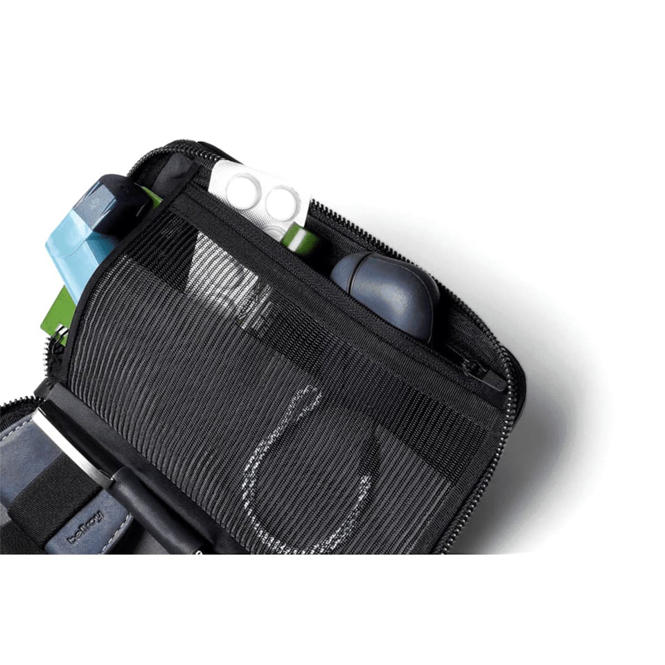 A black toiletry bag displaying various organisation compartments, including a mesh section and multiple small items.