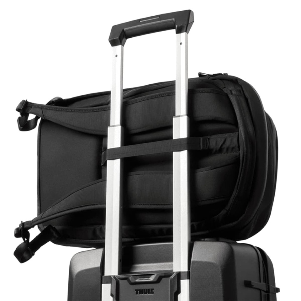 A black backpack attached to a wheeled suitcase, featuring straps for secure fastening and a sleek design.