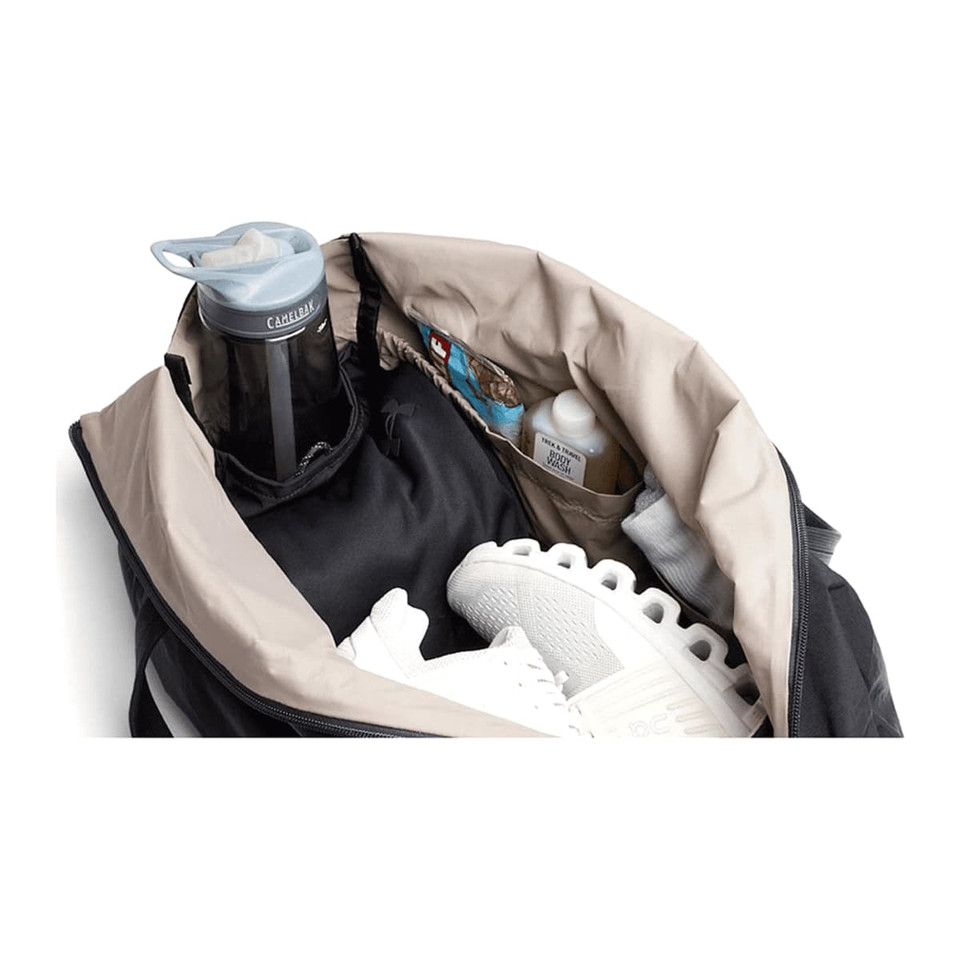 A black duffel bag opened to reveal a drink bottle, athletic shoes, and various smaller items inside.