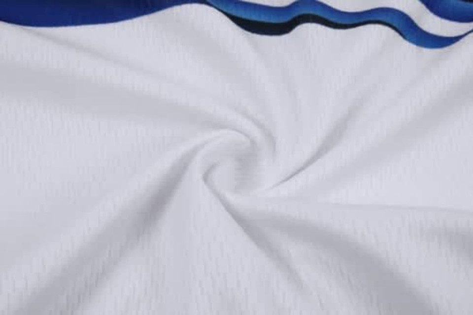 A close-up of white fabric with blue accents, featuring a textured pattern suitable for cycling team wear.