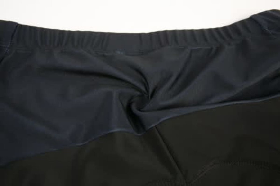 A close-up view of a cycling jersey featuring a dark navy and black design, with a logo on the back.