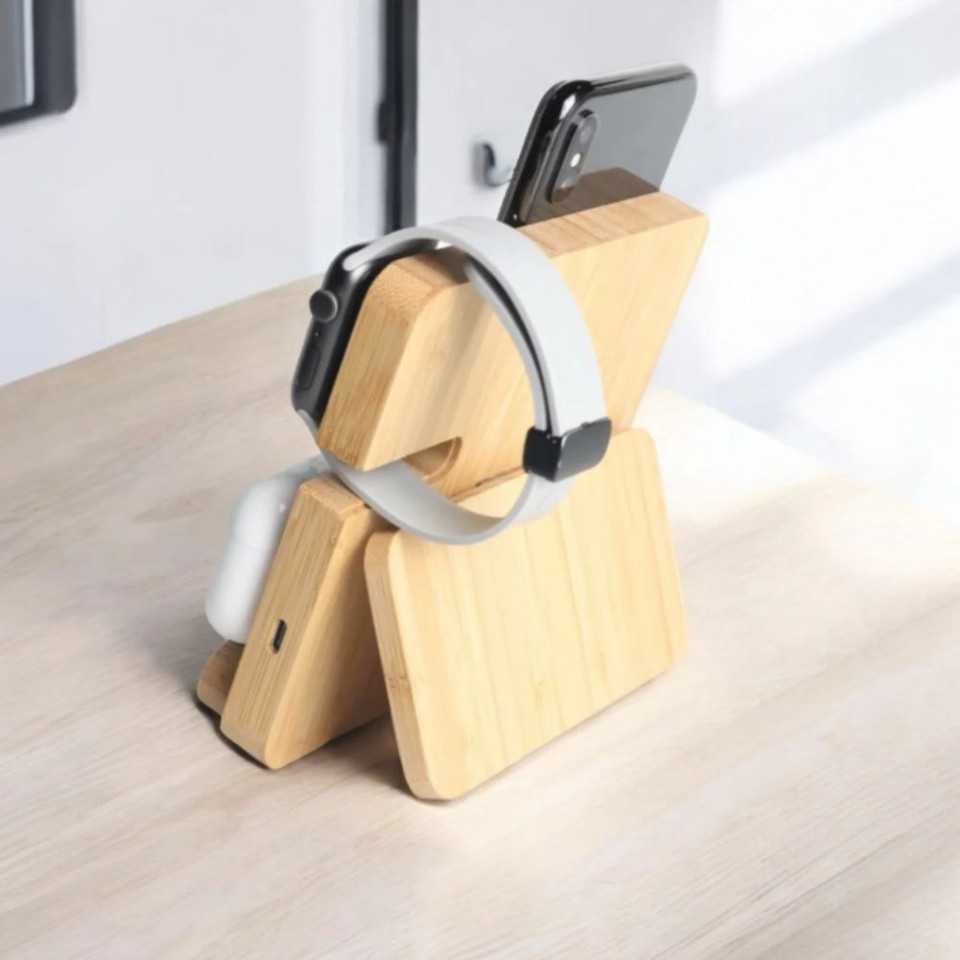 Wooden charging stand for smartphone, smartwatch, and earbuds on desk.