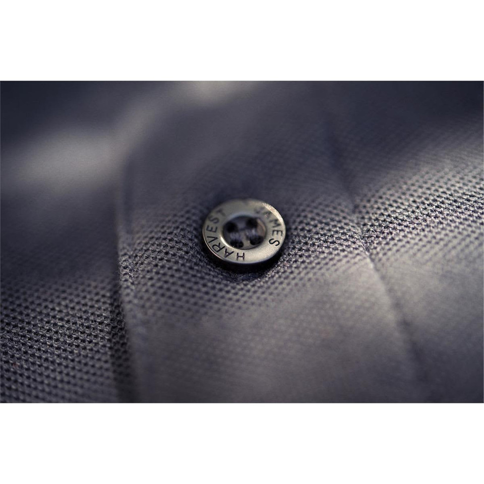 A close-up of a grey polo shirt featuring a black button with a logo. The fabric has a textured finish.