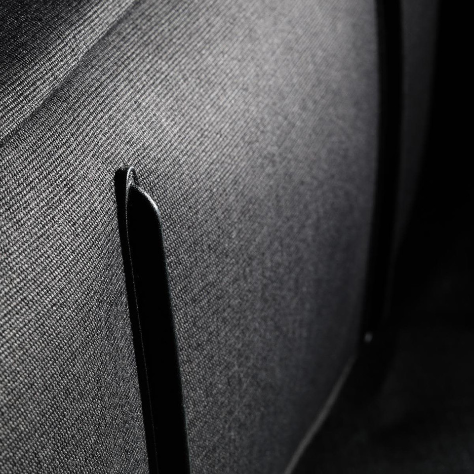 A close-up of fabric showing a textured black surface with a black trim detail. The material appears durable and structured.
