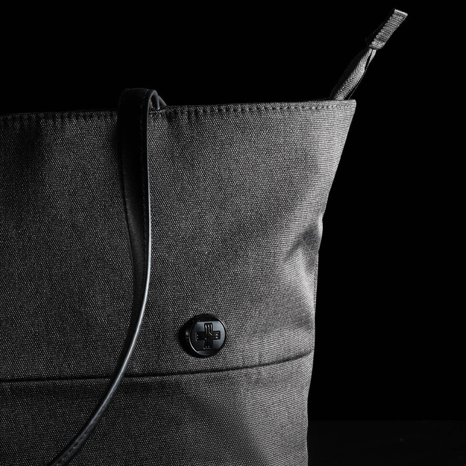 A black tote bag with a structured design and a sleek shoulder strap, featuring a circular logo.