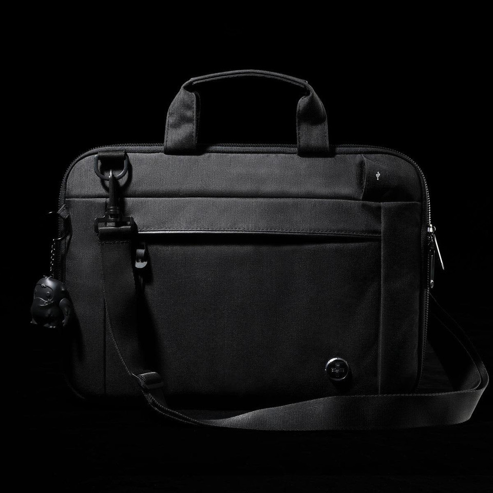 A black laptop sleeve with a handle and adjustable strap, featuring a front pocket and a small attached keychain.