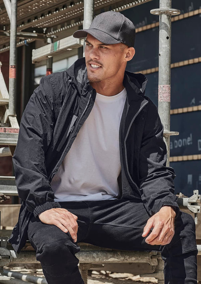A man wearing a black unisex packable rain jacket sits on scaffolding. The jacket features a hood and has a logo.