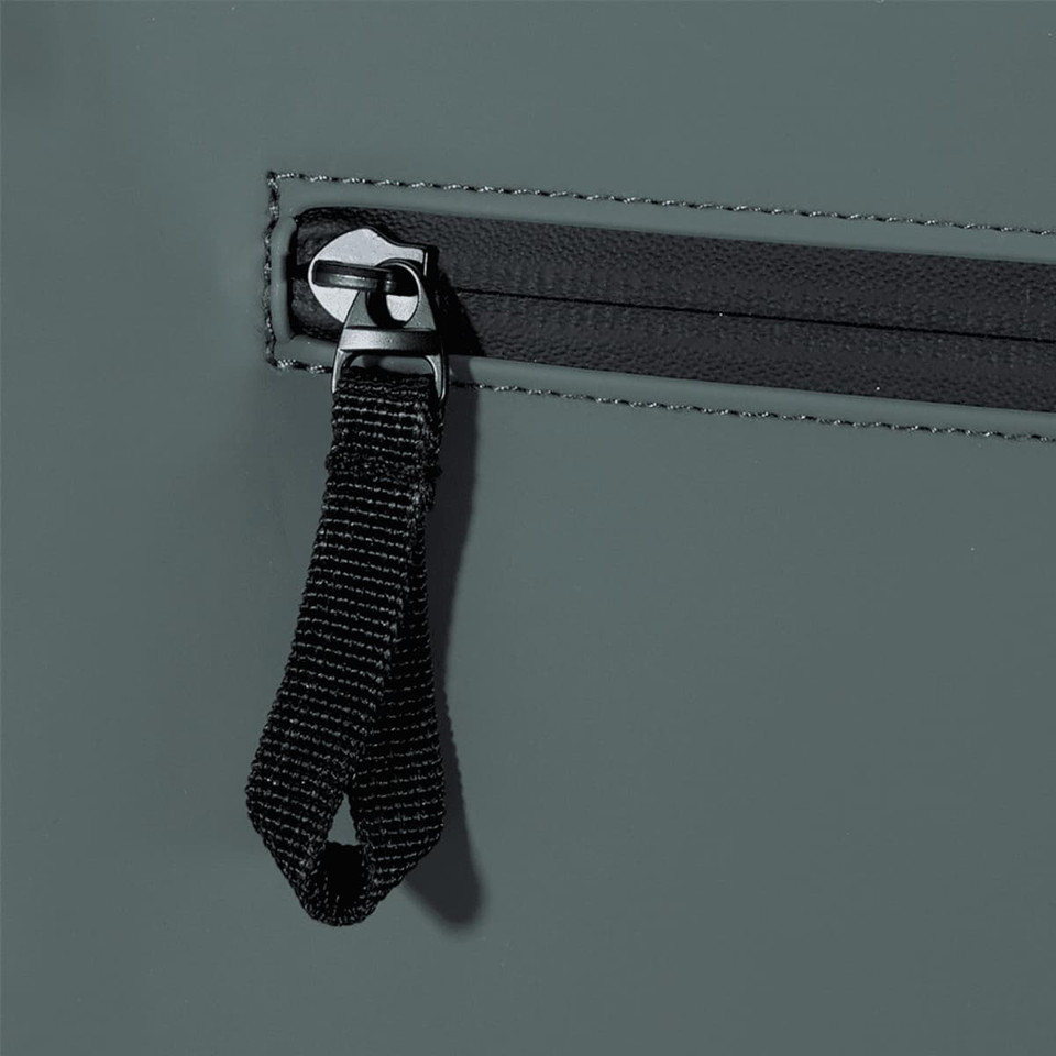 A close-up of the grey Resi Recycled Roll-Top 18L Backpack showing the zip and pull tab design.