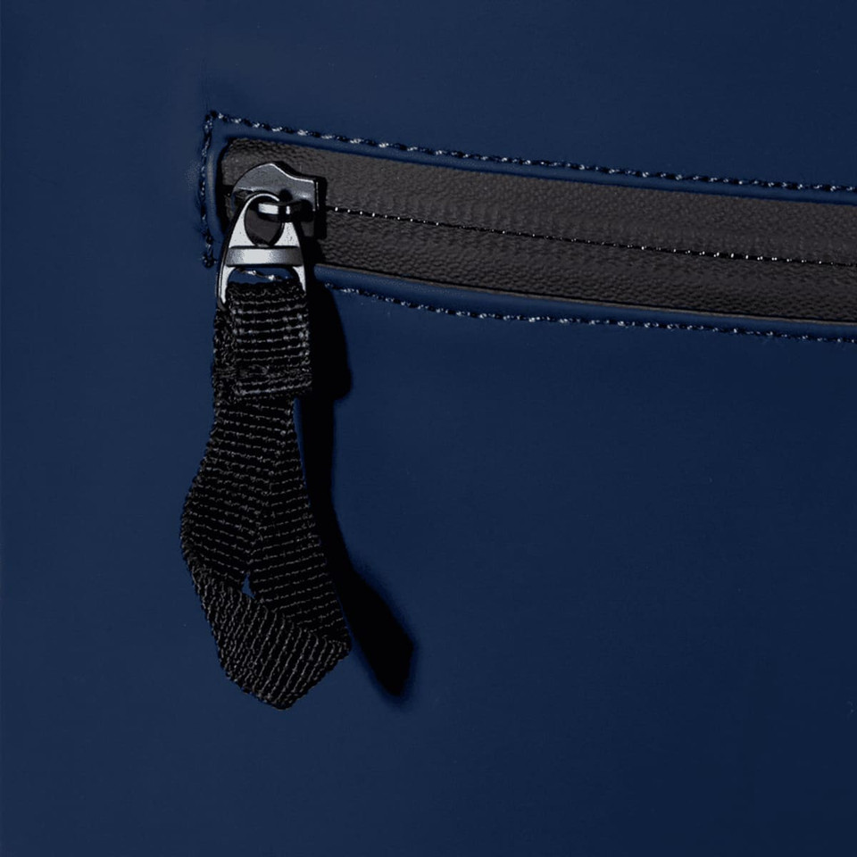 A navy blue roll-top backpack featuring a zippered pocket with a black pull tab and stitching details.