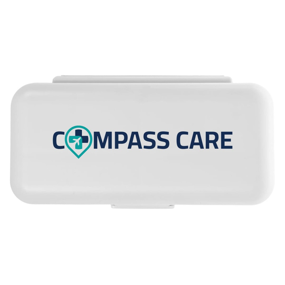 A compact pill organizer featuring a white exterior with a logo that reads "COMPASS CARE."