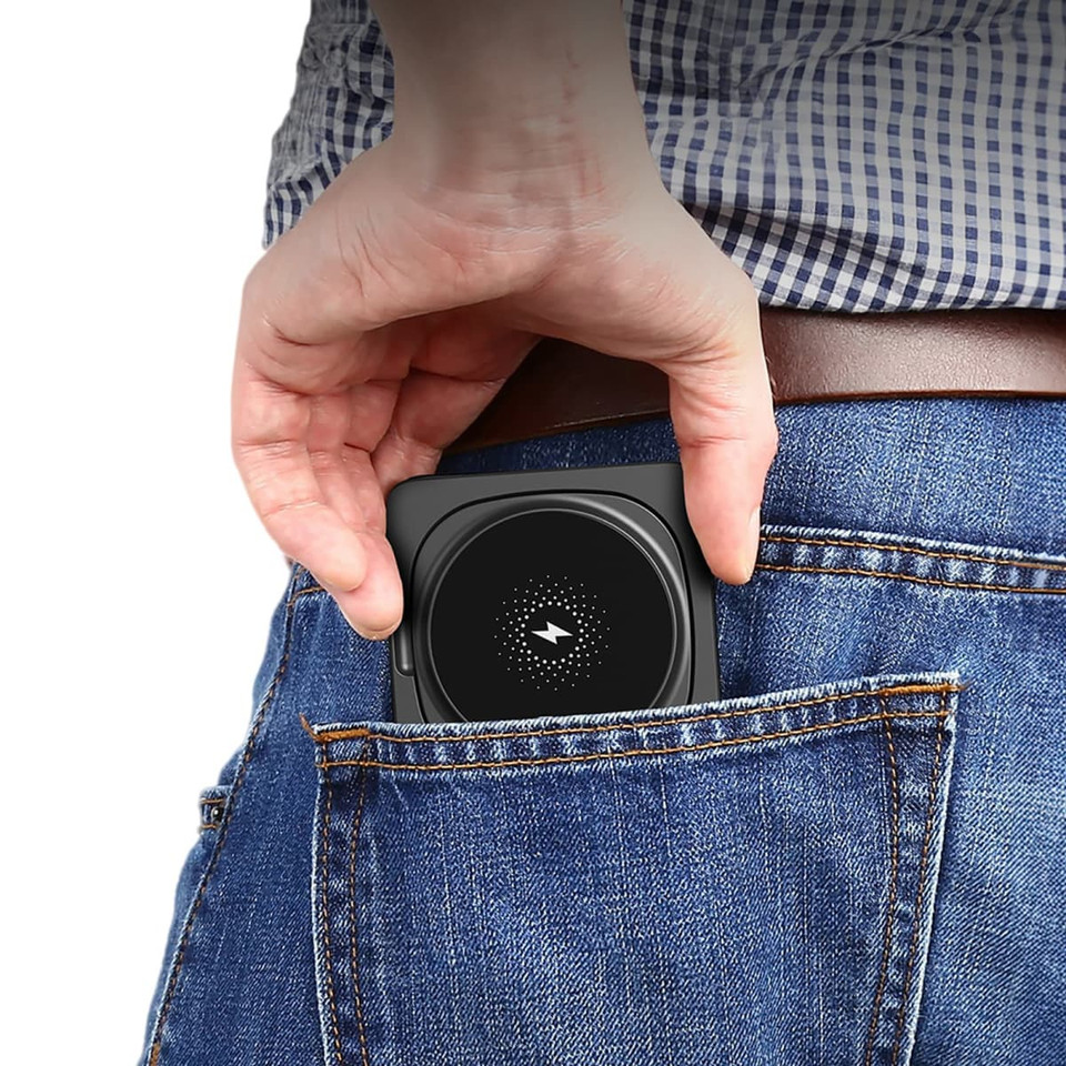 A compact black wireless charger is being pulled from a back pocket of blue jeans.