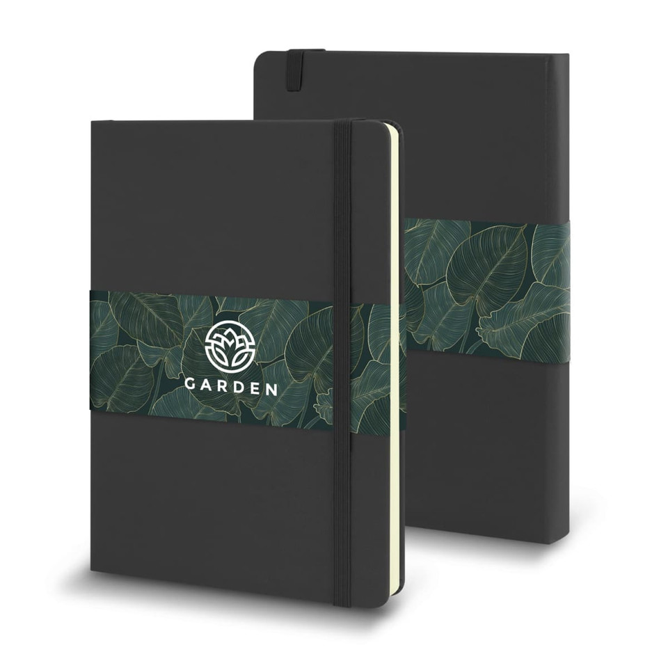 A large, black Moleskine Classic Hard Cover Notebook with a green leaf-patterned band and an emblem.