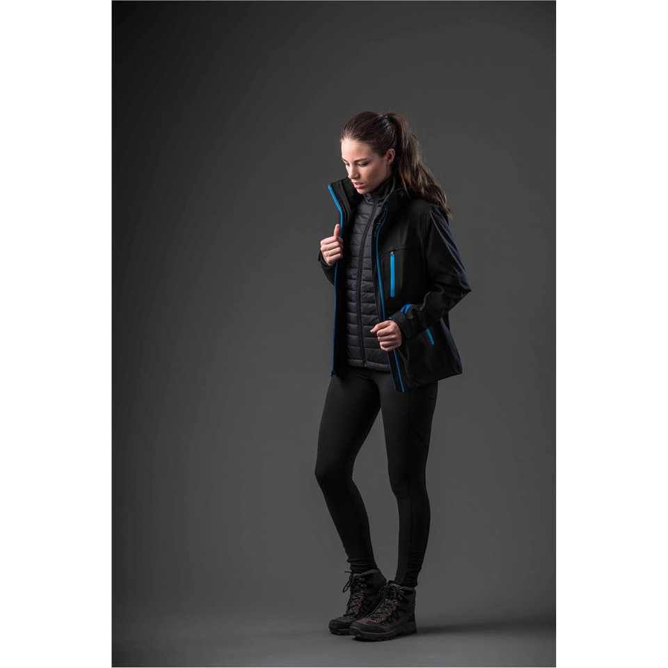 A woman wearing a black jacket with blue accents, paired with sleek black leggings and hiking boots.