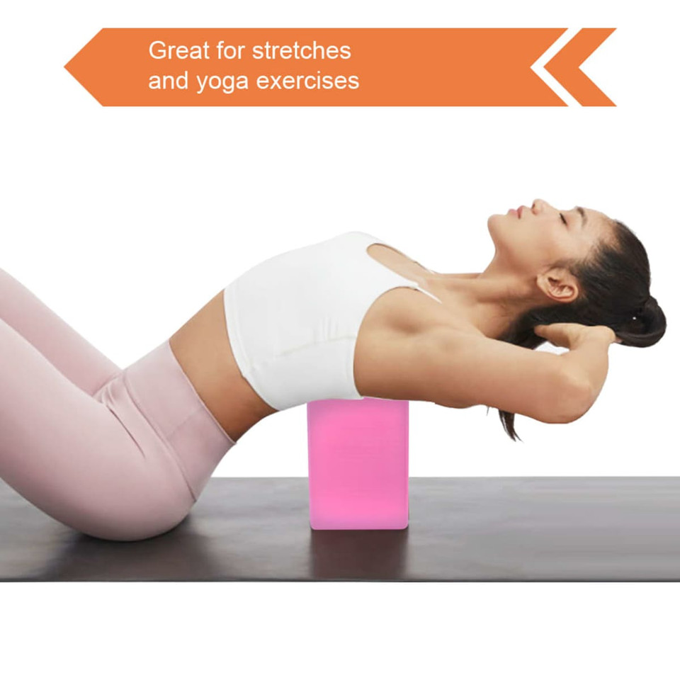 A pink EVA yoga block placed on a mat, used for stretching and yoga exercises. A person performs a pose with it.