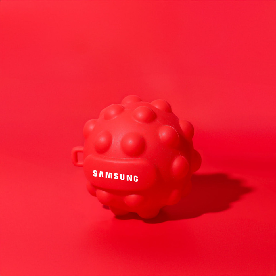 A bright red stress ball with a textured surface and a logo on one side.