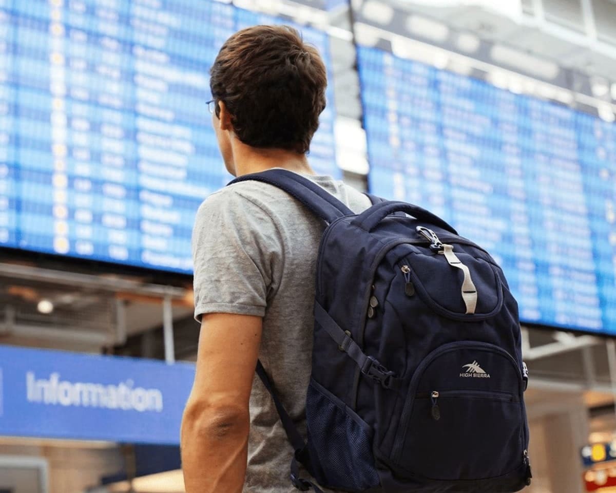 A man in an airport terminal wearing a High Sierra backpack