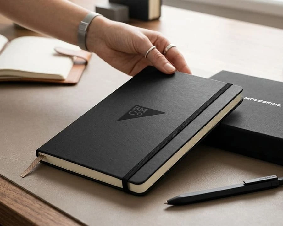 A woman holding up a Moleskine notebook