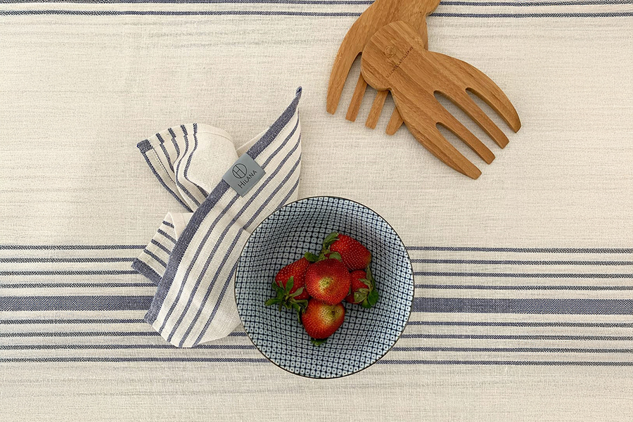 A bowl of strawberries on top of hilana branded blanket
