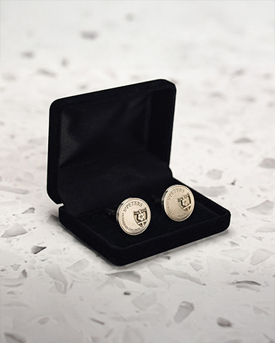 Elegant cufflinks displayed in an open black velvet box, on a speckled white surface