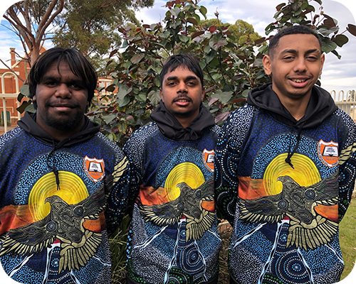 Three young men wearing matching vibrant hoodies with indigenous art 