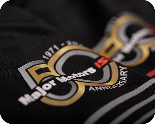 Close-up of a black fabric featuring a gold and silver 50th Anniversary logo for major motors
