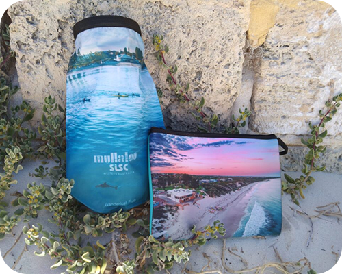 Two bags with beach scenes lean against a stone wall
