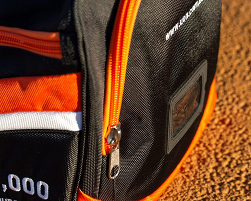 Close-up of a black and orange sports bag on a textured surface
