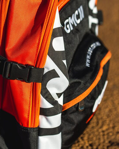Close-up of a colourful backpack with bright orange fabric and bold black and white lettering
