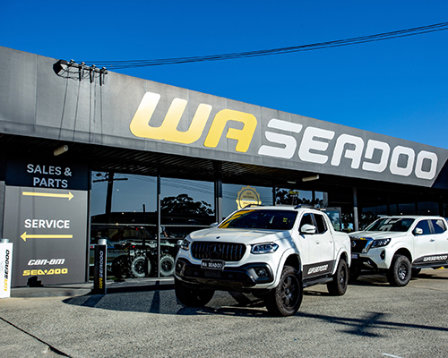 Two white trucks with graphics parked in front of a Seadoo store, highlighting the store's exterior and branding