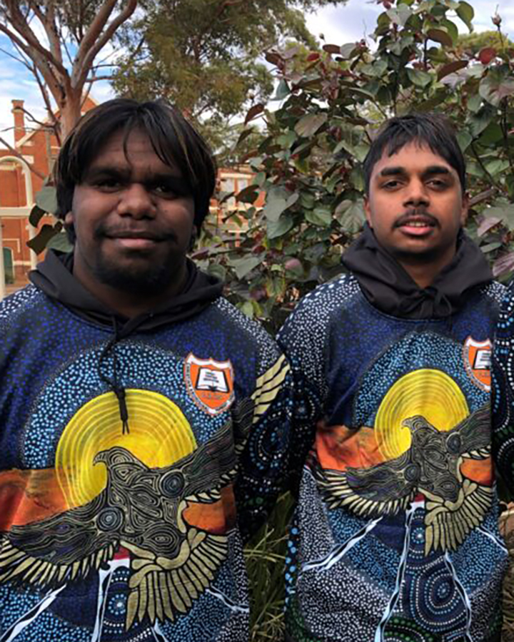 Two students are wearing the same hoodies featuring Peter Farmer's Aboriginal art