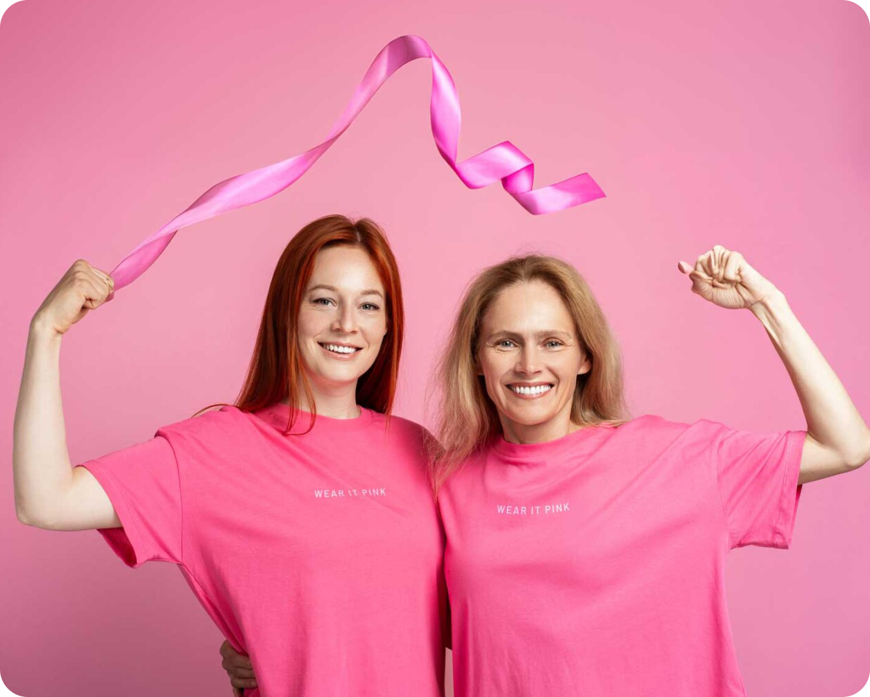 Two women wearing pink shirts
