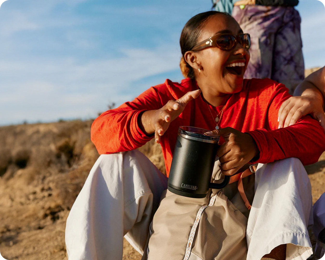 Smiling woman holding camelbak travel mug