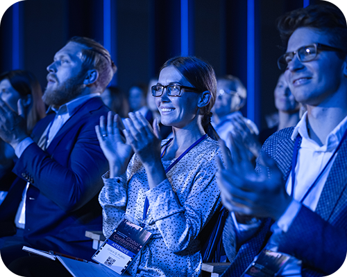 Audience clapping in a dimly lit conference room