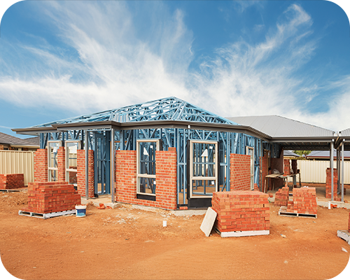 A partly constructed house with exposed blue steel framework and red brick walls under clear blue sky