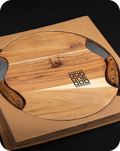 a chapter one advisors branded round wooden custom charcuterie board with two recessed handles on each side