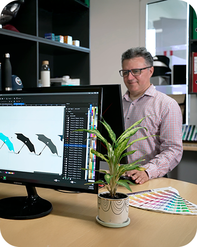 Man in glasses smiling while working on graphic design software at a desk