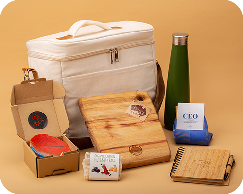White cooler bag, green bottle, cutting boards, notebook, colourful feathers in a box, business cards, and cotton bags