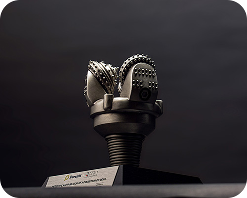A metallic drill bit award with intricate details sits on a pedestal