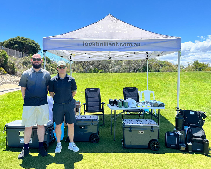 Two happy golfers standing by a Look Brilliant branded tent