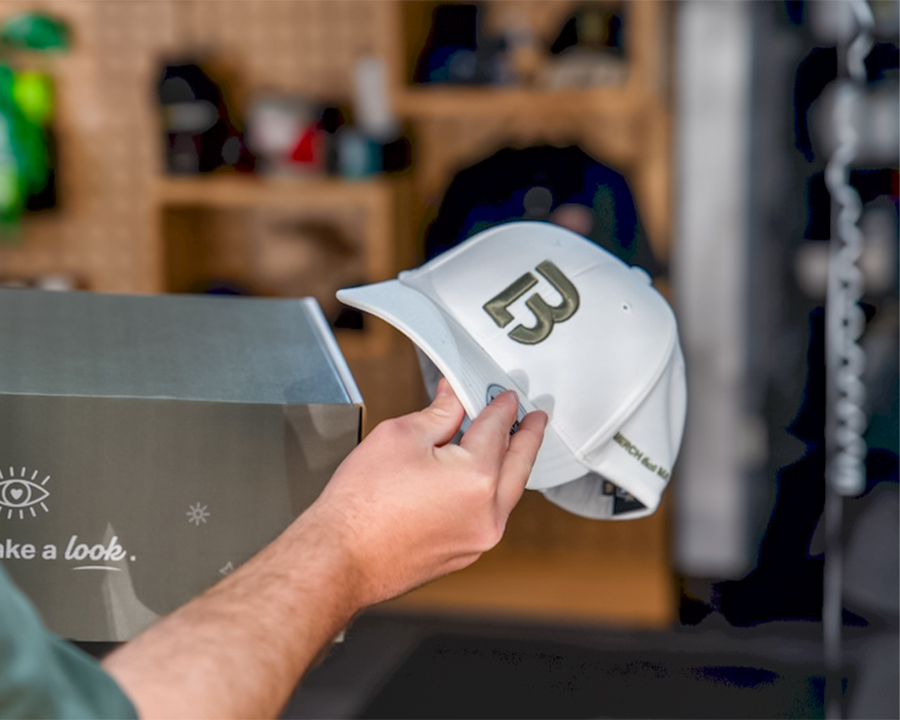 Man holding a white Look Brilliant cap