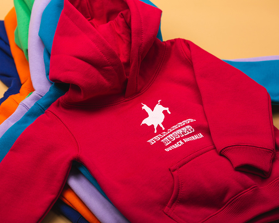 A stack of colourful nullarbor muster club hoodies