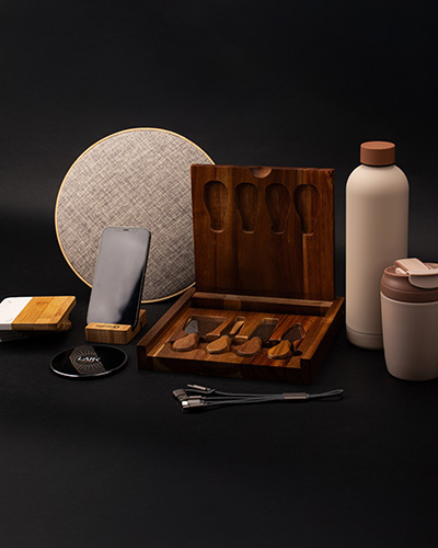 A collection of eco-friendly items including a wooden knife set, reusable bottles, a bamboo phone stand, and cables