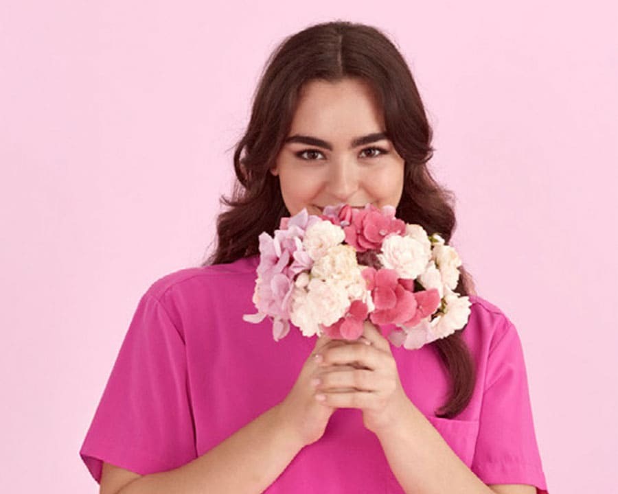 A woman wearing pink scrubs holding flowers