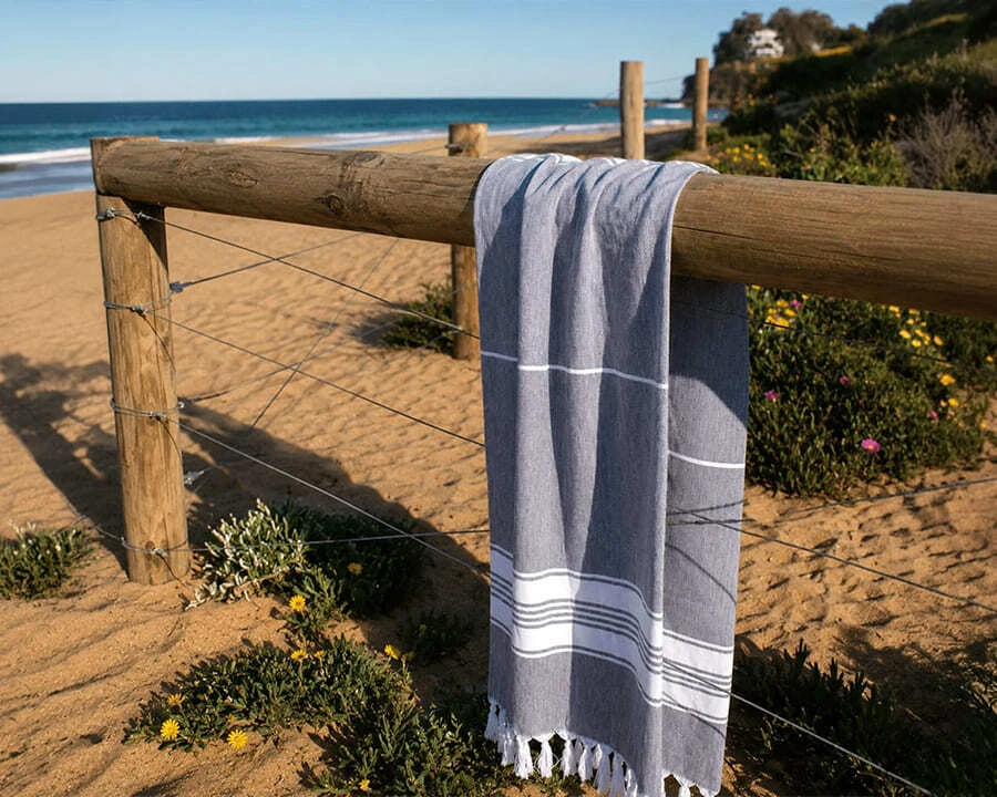 A grey trekk cotton turkish towel hanging at a beach